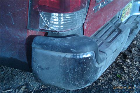 2009 Toyota Tacoma - Rear view of a red pickup truck, showing a step bumper and a damaged taillight.