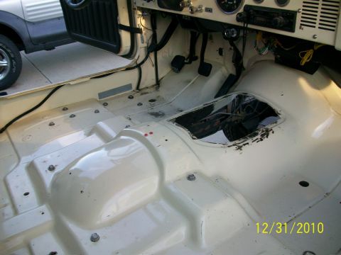 1986 Jeep Wagoneer - The interior of a Jeep is shown with the carpet removed, revealing the floor pan and exposed components.
