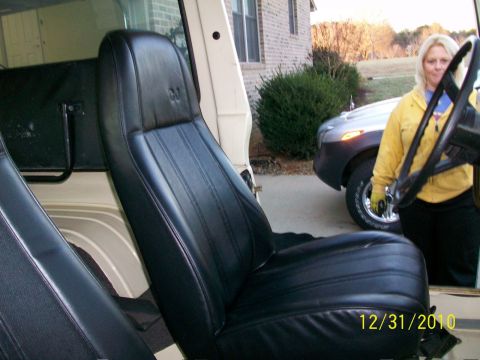 1986 Jeep Wagoneer - A woman stands by the steering wheel of a Jeep, with another vehicle visible in the background.