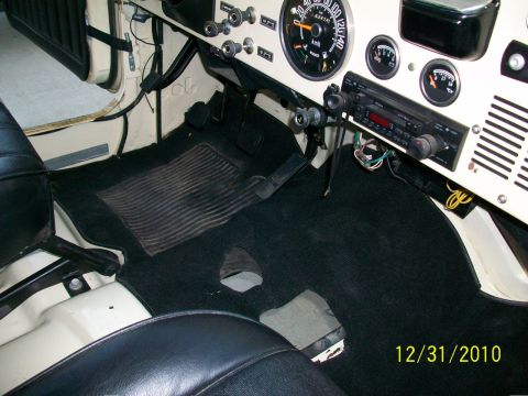 1986 Jeep Wagoneer - The interior of a Jeep shows a dashboard with gauges, a radio, and black carpeting on the floor.