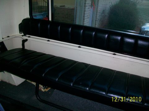 1986 Jeep Wagoneer - The interior of a vehicle shows a black vinyl bench seat with white paneling.