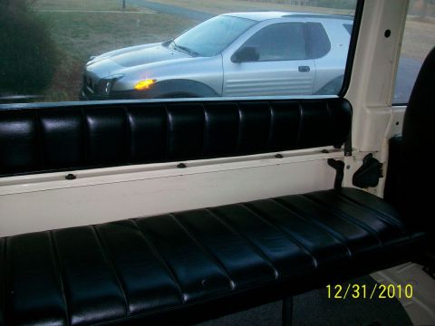 1986 Jeep Wagoneer - A silver SUV is visible through the window of a vehicle's interior, showing its side profile.