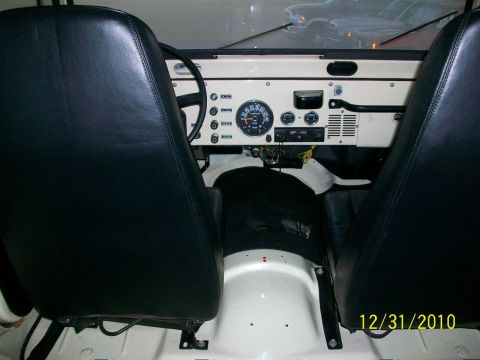 1986 Jeep Wagoneer - The interior of a Jeep shows black seats and a cream dashboard with round gauges and a steering wheel.