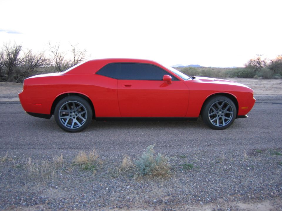 Red Dodge Challenger coupe side profile parked on a desert roadside