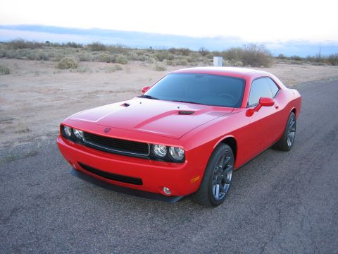 2010 Dodge Challenger - A red Dodge Challenger sits on a road with desert brush and a cloudy sky in the background.