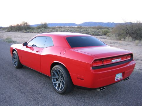2010 Dodge Challenger - A red Dodge Challenger is viewed from the rear, parked on a paved surface with a desert landscape in the background.