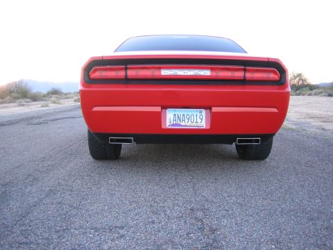 2010 Dodge Challenger - Rear view of a red 2010 Dodge Challenger, showing its distinctive taillights and dual exhaust.