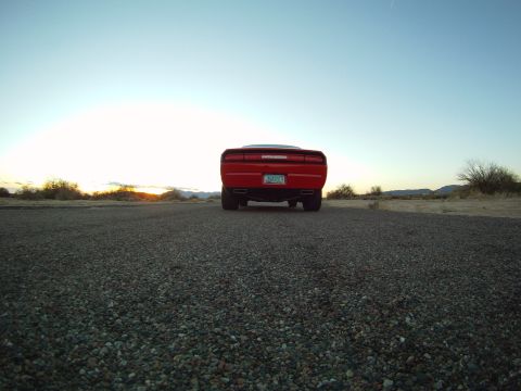 2010 Dodge Challenger - A red Dodge Challenger is seen from the rear on a gravel road during sunset.