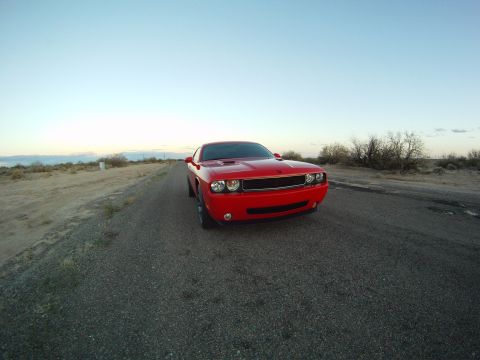 2010 Dodge Challenger - A red Dodge Challenger sits on a desolate road under a clear sky.