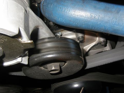 1990 Ford Bronco - A close-up view of the engine's belt tensioner pulley and serpentine belt system.