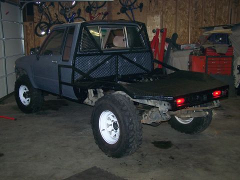 1988 Suzuki Samurai - This modified flatbed truck features a custom roll cage and oversized tires, suggesting off-road or utility use.