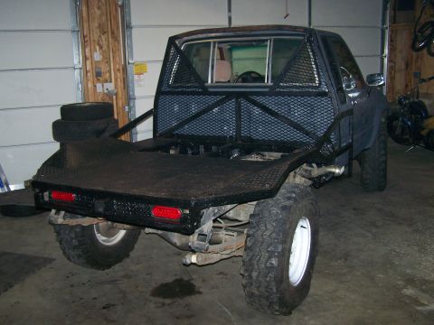 1988 Suzuki Samurai - Custom flatbed truck with a reinforced rear cage and diamond plate bed is parked indoors.