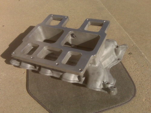 Bare aluminum 6-71 blower intake manifold for a V8 on a carpet mat, top deck and runners visible