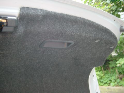 2003 Mazda 6 - The interior of a vehicle's trunk is visible, gray carpeting and a recessed handle.