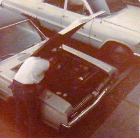 1968 Mercury Cougar - A person attends to the engine bay of a car, with a second vehicle visible in the background.