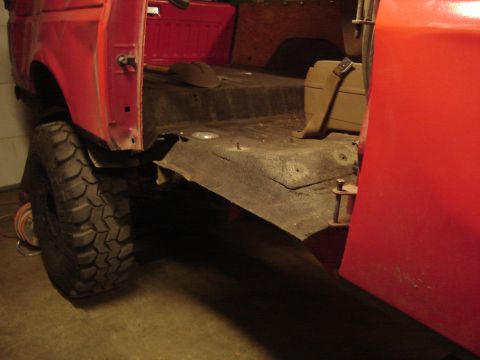 1989 Ford Bronco - Interior view of a red vehicle, focusing on the floor and a large tire.