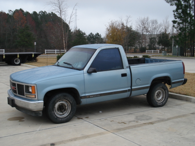 Light blue GMC pickup truck parked on pavement, side view