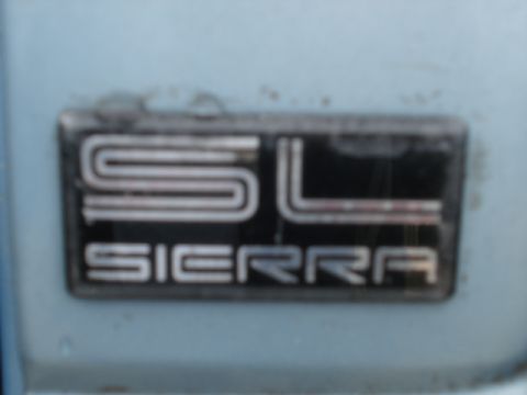 1979 Chevrolet C/K Pickup - A close-up shot focuses on the 'SL Sierra' emblem, a detail from a vehicle.