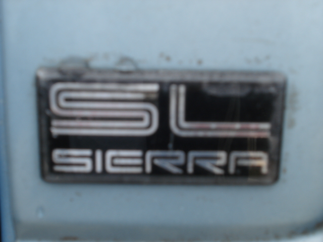 Close-up of an SL Sierra badge on a light blue vehicle