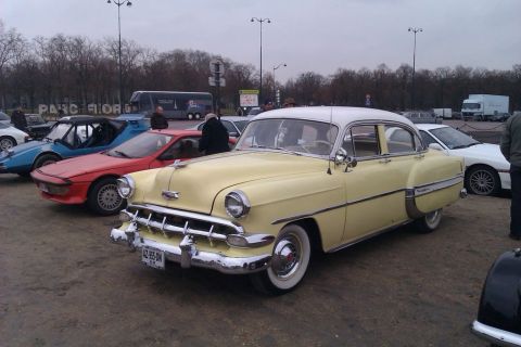 1991 Ford Crown Victoria - A vintage yellow and white sedan is parked alongside other vehicles under an overcast sky.