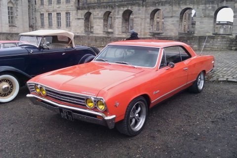 1991 Ford LTD Crown Victoria - This orange 1966 Chevrolet Chevelle coupe is parked next to a dark blue convertible in front of a stone building.