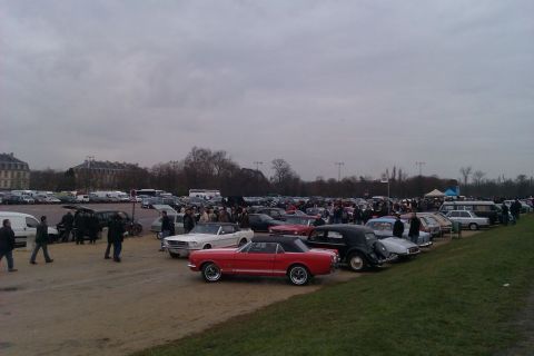 1991 Ford LTD Crown Victoria - A large gathering of cars and people at an outdoor event under a cloudy sky.