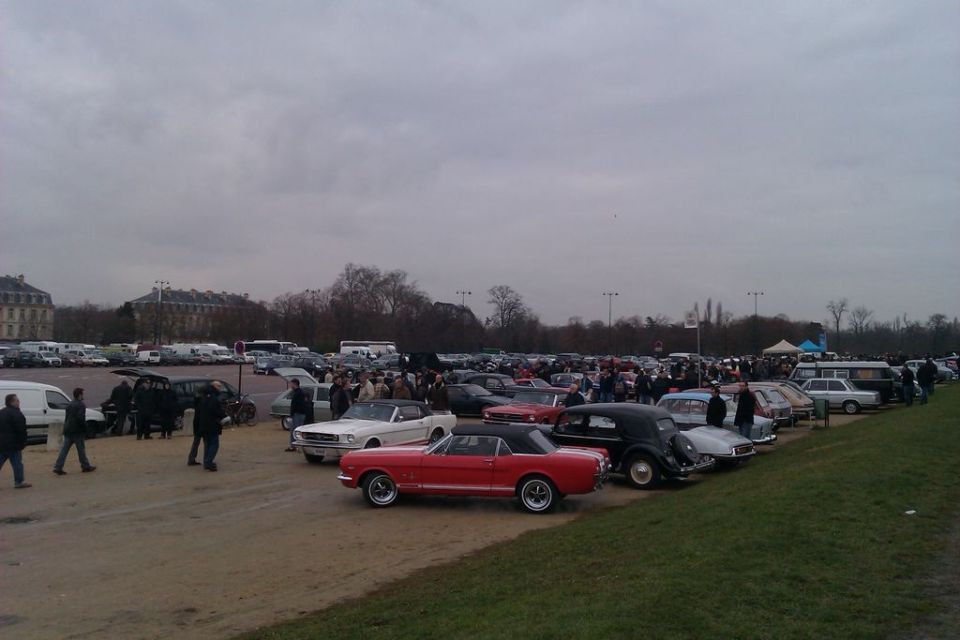 Outdoor car show with dozens of vehicles parked, including a red classic convertible in the foreground