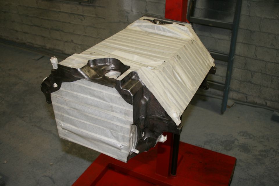 Engine block covered in protective wrap, mounted on a red stand