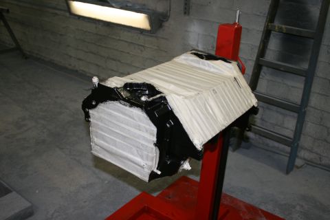 1973 Ford Ranchero - Engine block is partially covered with tape and paint, resting on a red engine stand.