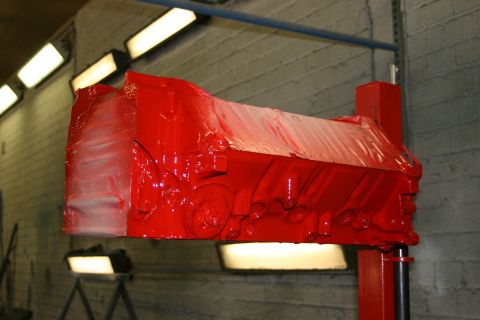 1973 Ford Ranchero - A red engine block is suspended and covered in plastic wrap, likely for painting or protection during a repair process.