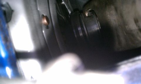 1990 Ford Mustang - A close-up view of a dark mechanical component a copper bolt, with a blurred blue object in the foreground.