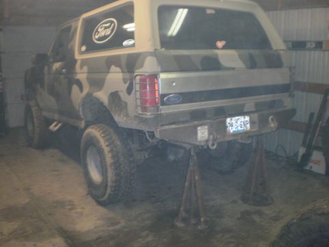 1995 Ford Bronco - Rear view of a lifted 1995 Ford Bronco with camouflage paint, undergoing work in a garage.