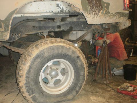 1995 Ford Bronco - A person works on the rear axle of a truck, which appears to be undergoing a repair or modification.