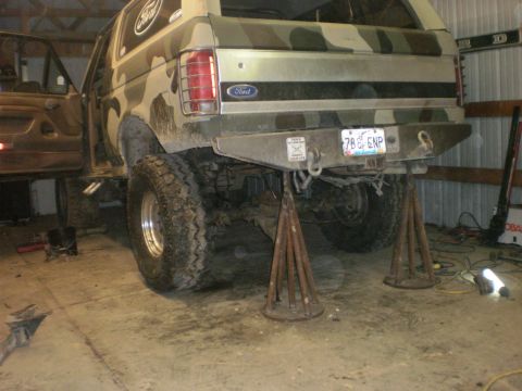 1995 Ford Bronco - This Ford Bronco, with a camouflage paint job, is raised on jack stands, showing its rear axle and aftermarket bumper.