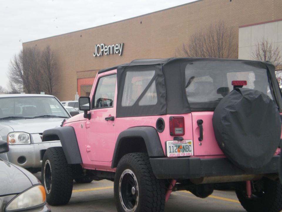 Pink Jeep Wrangler with soft top, spare tire cover, and custom license plate