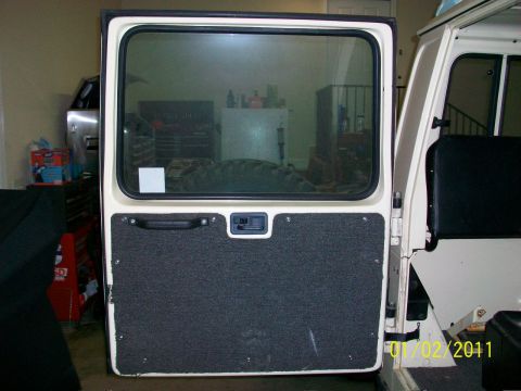 1986 Jeep Wagoneer - Rear door panel of a vehicle, showing the interior lining and handle.