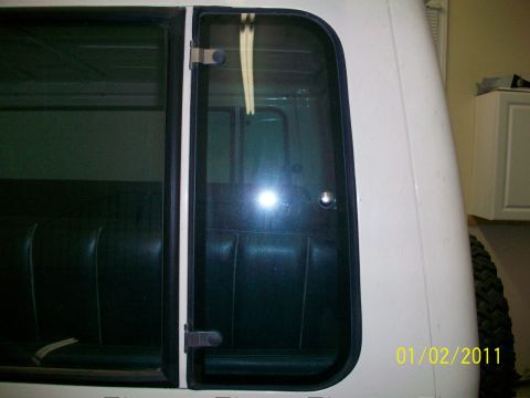 1986 Jeep Wagoneer - Close-up of the rear side door and window of a white SUV, revealing the interior seating.
