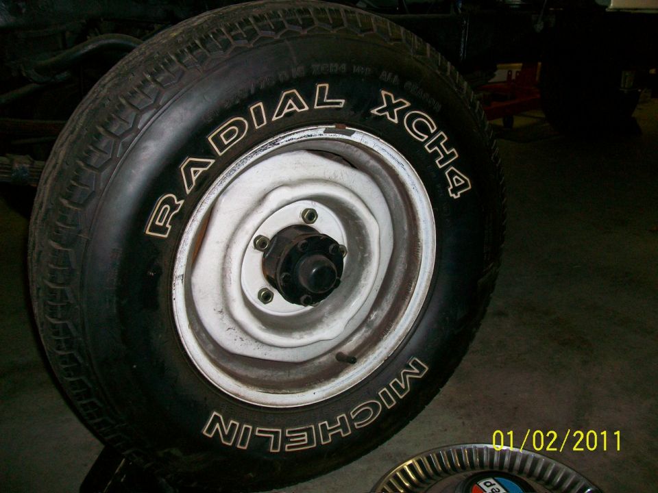Michelin Radial XCH4 tire on white steel wheel with exposed hub and lug studs in garage