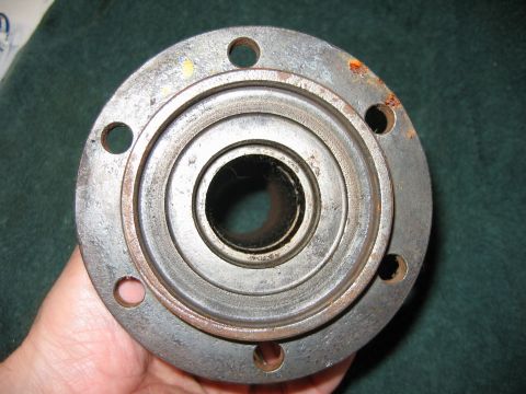 1992 Ford Bronco - A hand holds a metal wheel hub assembly, showing signs of wear and rust.