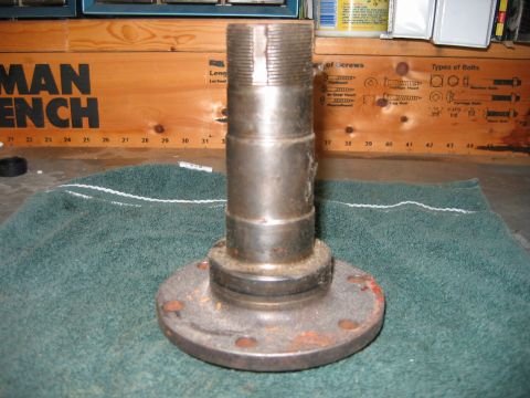 1992 Ford Bronco - A metal spindle part rests on a towel, with a workbench and tool diagrams visible in the background.