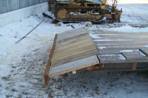 1963 Hummer H3 - A trailer with a wooden ramp is parked in the snow, with a bulldozer visible in the background.