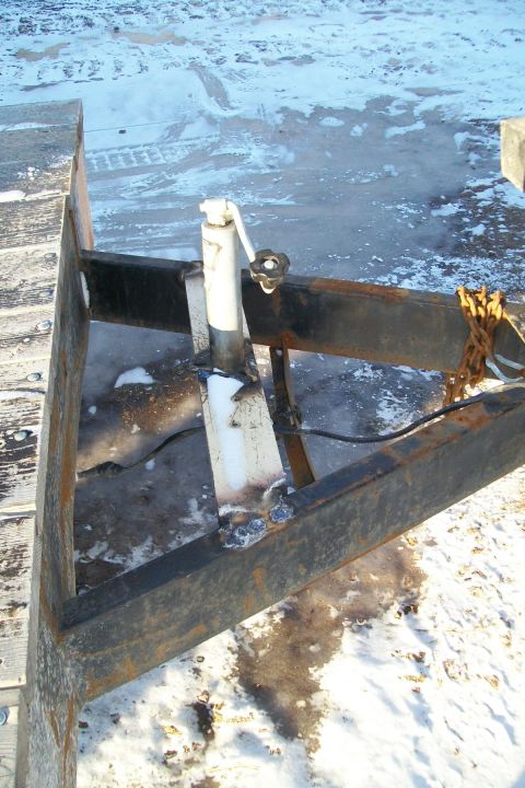 1963 Hummer H3 - Close-up of a trailer's tongue jack mechanism, showing welds and a chain.