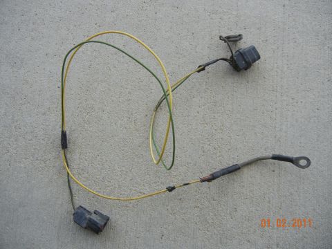 1996 Ford Bronco - A wiring harness with two connectors and a ring terminal lies on a concrete surface.