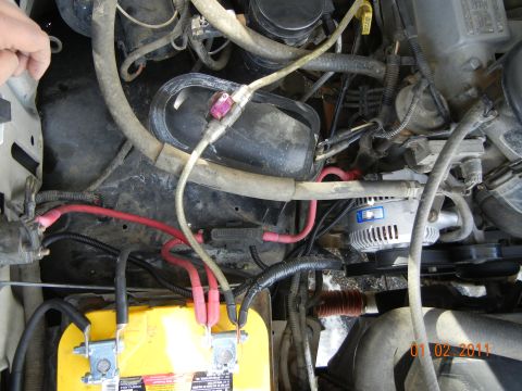 1996 Ford Bronco - Close-up view of a vehicle's engine bay, showing a yellow battery and alternator.