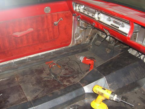 1964 Ford Ranchero - Interior view of a 1964 Ford Ranchero, showing the dashboard, door panel, and floor with tools present.