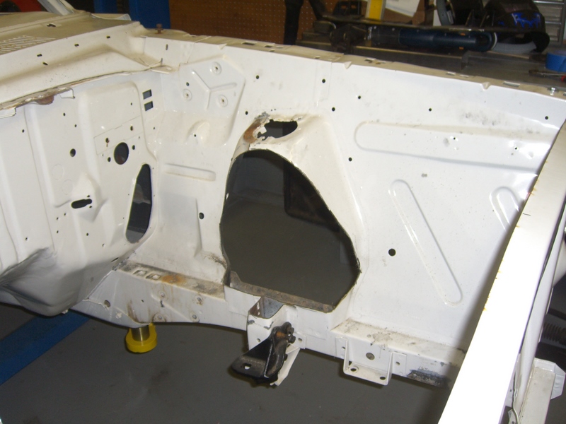 White painted car engine bay with rust spots and cutouts for components