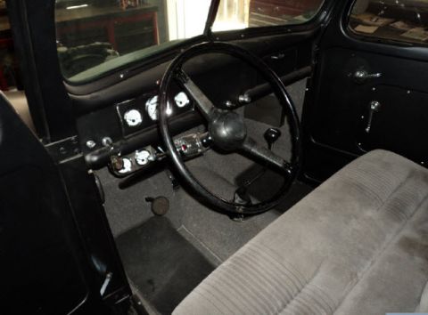 1941 Ford Pickup - The interior of a 1941 Ford Pickup features a classic dashboard, steering wheel, and a textured seat.