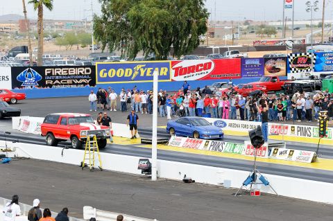 1979 Ford Bronco - A red 1979 Ford Bronco is lined up at the start of a drag race, with a crowd watching in the background.