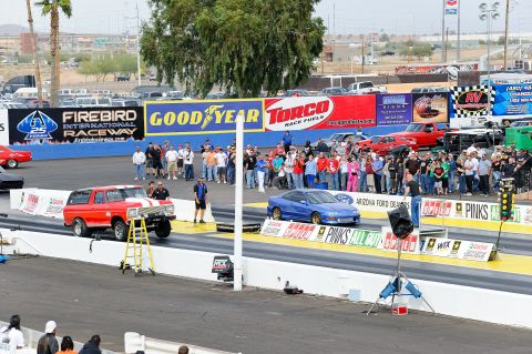 1979 Ford Bronco - A red SUV is staged on a drag strip, with a ladder positioned beside it.