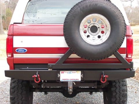 1990 Ford Bronco - Rear view of a 1990 Ford Bronco a red and white paint scheme and a spare tire mounted on a swing away carrier.